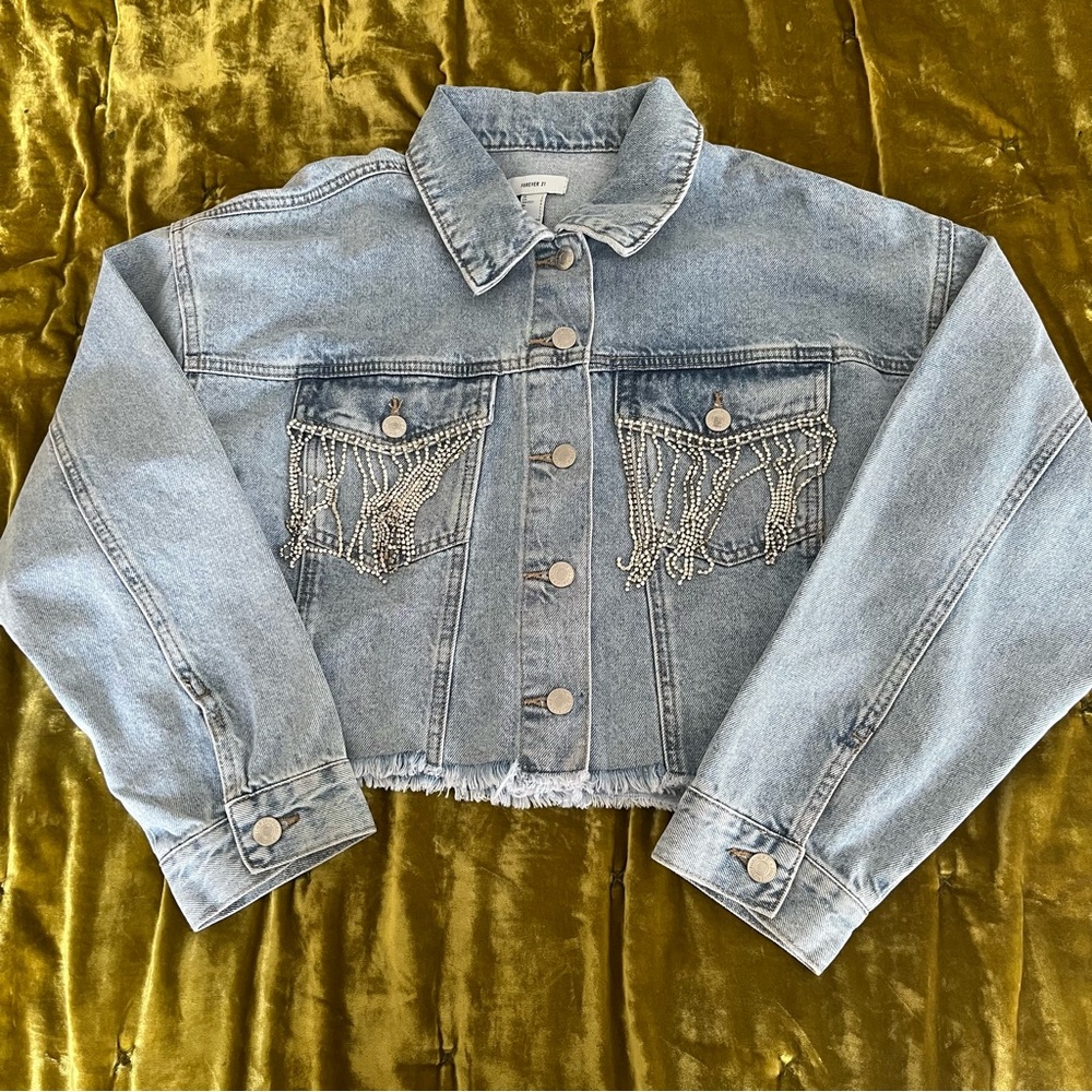 Light denim cropped jean jacket with rhinestone fridge front and back.